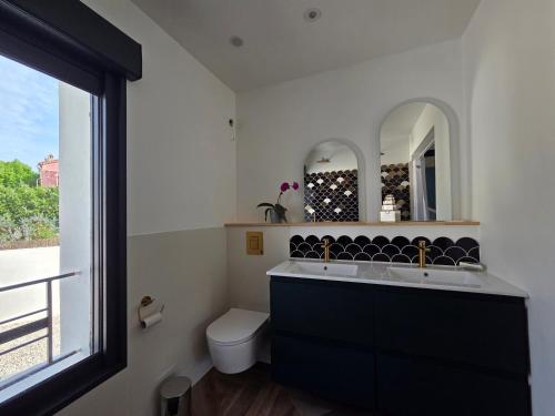 a bathroom with a sink and a toilet and a window at Villa Lumineuse in Nyons