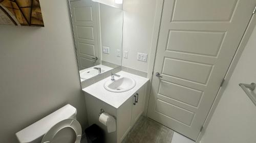 a bathroom with a sink and a toilet and a mirror at Comfy-home in YYC
