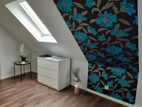 a room with a dresser and blue flowers on a wall at Ferienwohnung Sternfeld in Osburg
