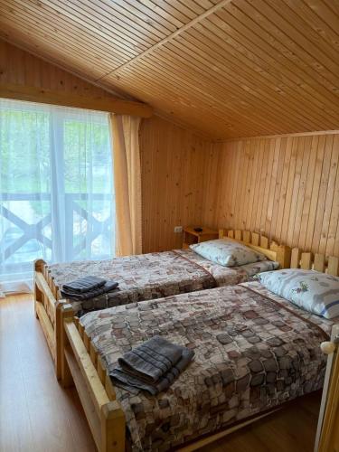 two beds in a wooden room with a window at Cube in Kvasy