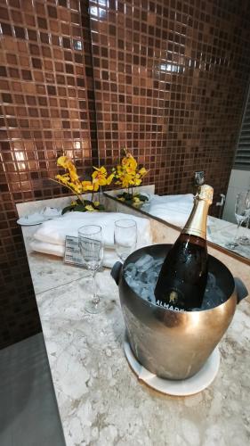 a bottle of champagne in a bucket on a table with glasses at Foz Presidente Comfort Hotel in Foz do Iguaçu