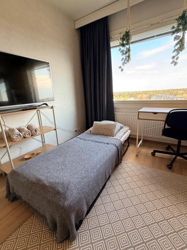 a bedroom with a bed and a desk and a window at The Treetop Apartment in Turku