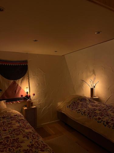 a bedroom with two beds and two lights on the wall at Chez Firmin in Manhay