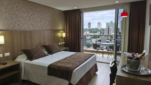 a hotel room with a bed and a large window at Foz Presidente Comfort Hotel in Foz do Iguaçu