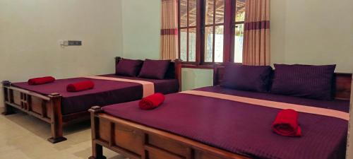 two beds in a room with red pillows on them at MSM Surf Camp in Arugam Bay