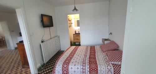 a bedroom with a bed and a tv on the wall at Gîte des pêcheurs, Gorges du Tarn in Mostuéjouls