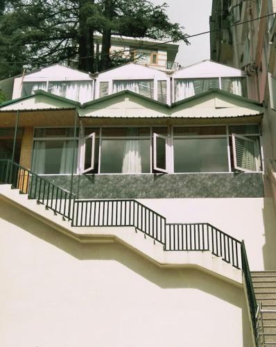 a large house with stairs in front of it at Hotel Lords Regency - Connected to the Mall Road in Shimla