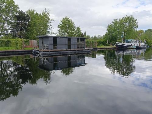 a house on a dock on a river with a boat at Houseboat Enjoy with 200m Private Garden on the Lake in Vinkeveen