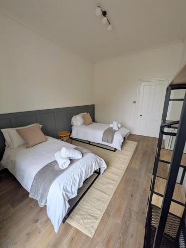 two beds in a room with wooden floors at Modern Flat - Main St, Campbeltown in Campbeltown