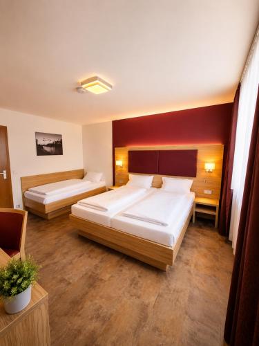 two beds in a hotel room with red walls at Hotel Pale Wolfsburg 24H Self Check-in in Wolfsburg