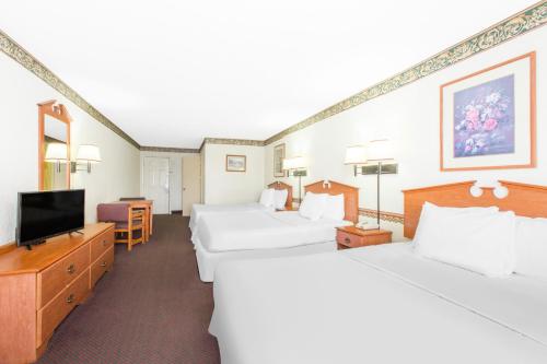 a hotel room with two beds and a flat screen tv at Days Inn & Suites by Wyndham Marshall in Marshall