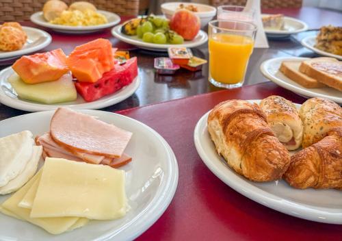 a table with plates of breakfast foods and orange juice at Hotel Rainha dos Apóstolos in Aparecida