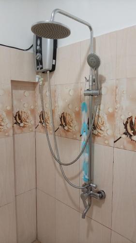 a shower head in a bathroom with flowers on the wall at The Sun Horse Villa in Unawatuna