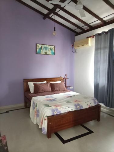 a bedroom with a bed in a room with purple walls at The Sun Horse Villa in Unawatuna
