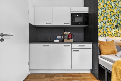 a kitchen with white cabinets and a couch at Design Mini Studio No 9, Küche, Parkplatz, Wifi by BALANCED in Holzkirchen