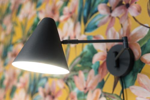 a lamp hanging from a wall with a flower wallpaper at Design Mini Studio No 9, Küche, Parkplatz, Wifi by BALANCED in Holzkirchen
