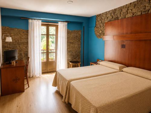 ein Hotelzimmer mit Bett und Fernseher in der Unterkunft Hotel Torrepalacio in Proaza