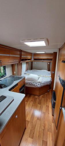 a kitchen with a bed in the middle of a room at Gezellige luxe caravan met zwembad in zuid- Bourgogne in Anglure-sous-Dun