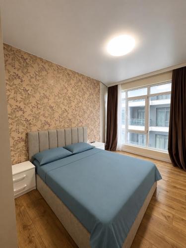 a bedroom with a blue bed and a window at Bright large apartment in White Sails in Batumi
