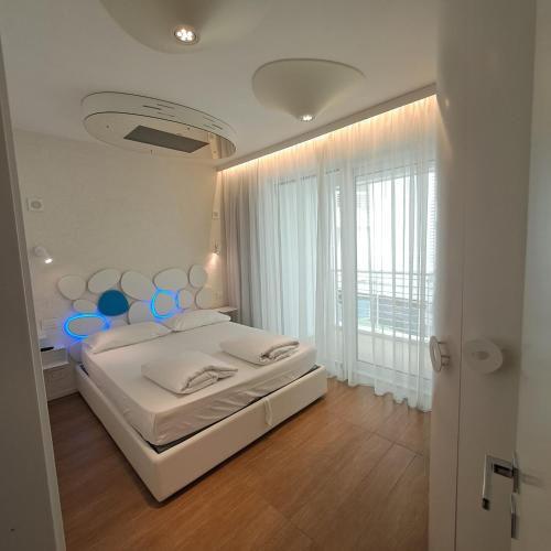 a white bedroom with a bed and a large window at Marina Verde Resort Official in Caorle