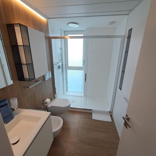 a bathroom with a sink and a toilet and a window at Marina Verde Resort Official in Caorle
