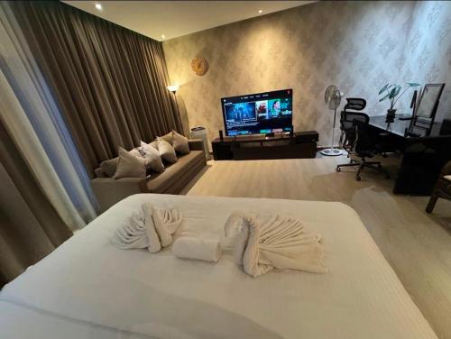 a living room with a white bed and a tv at Aika Homestay in Shah Alam