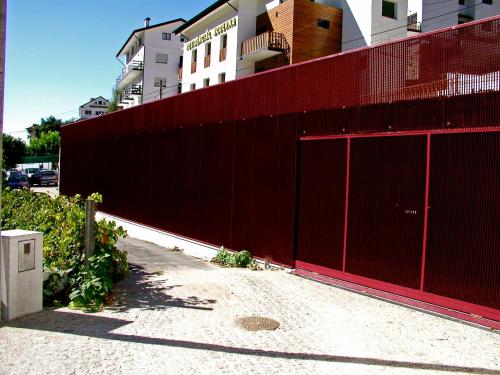 a red fence is next to a building at Hotel Central Jardim in Geres
