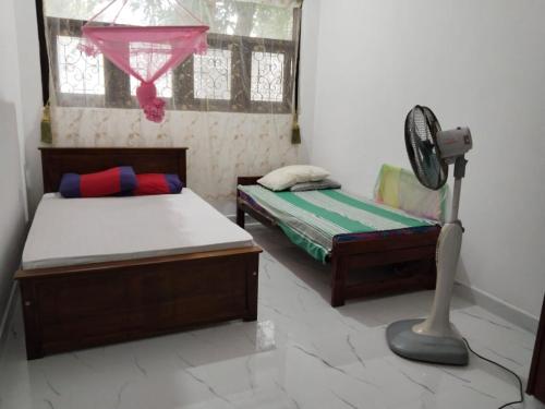 a bedroom with two beds and a fan at Jayasiri Riverfront Home in Lansiyawatta