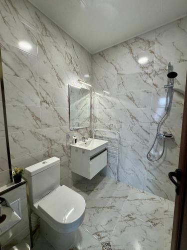 a white bathroom with a toilet and a sink at Стаи за гости- Maria Elegance in Pavel Banya