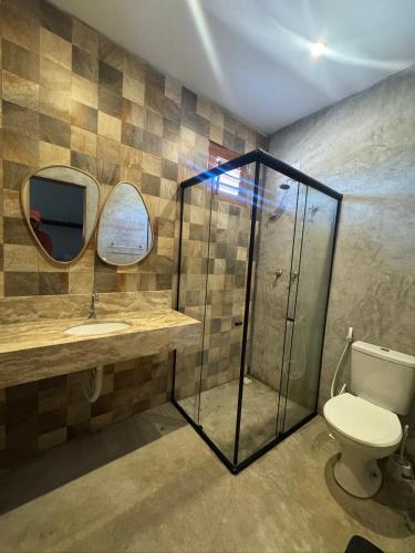 a bathroom with a glass shower and a toilet at Casita Beach House in Itarema