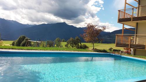 a swimming pool in front of a building with mountains at Bauernhofresidence Leierhof in Rodengo