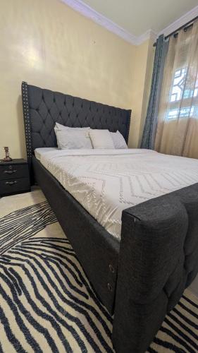 a bedroom with a large bed with a black headboard at Cozy Homes in Bungoma