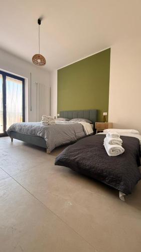 a bedroom with two beds and a green wall at Dimora Zaffiro in LʼAquila
