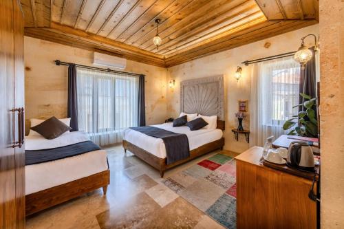 a bedroom with two beds in a room with wooden ceilings at Rocca Stone House in Göreme