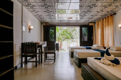 a bedroom with two beds and a table and chairs at Surf Resort Arugambay in Arugam Bay