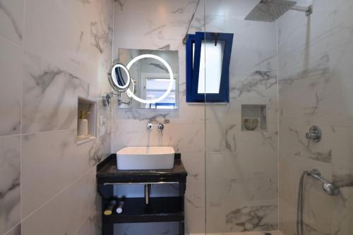 a bathroom with a sink and a mirror and a shower at Ocean View Rooms in Paralia Vrachou