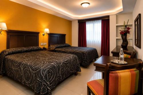 ein Hotelzimmer mit zwei Betten und einem Tisch in der Unterkunft Hotel Gran Via Veracruz in Veracruz