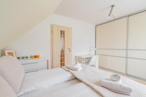 a white bedroom with towels on a bed at Apartament Malinowy-Osiedle Malinowa 68, Zieleniewo in Zieleniewo