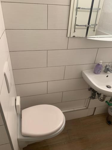 a white bathroom with a toilet and a sink at Seven’S Apartments in Löhnberg