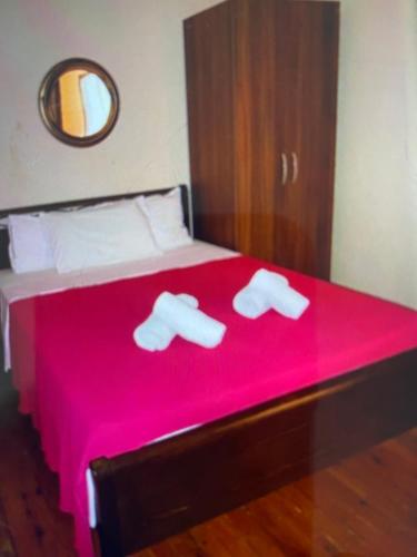 a bedroom with a red bed with two white slippers at VILLA MAKRI 2 in Makri