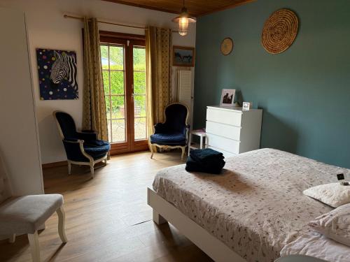 a bedroom with a bed and two chairs and a window at Chez Tantine Nadine in Couvin