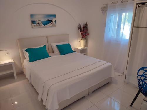 a white bedroom with a large bed with blue pillows at JB Villa in Mesaria