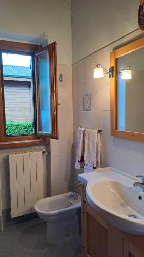 a bathroom with a sink and a toilet and a window at B&B Hannelore in Vilminore