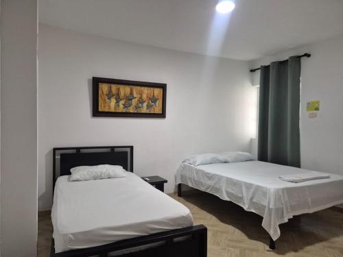 a room with two beds and a painting on the wall at caribepremiumvalledupar in Valledupar