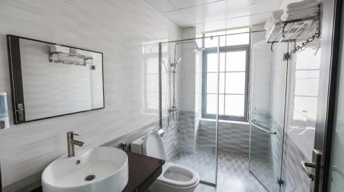 a white bathroom with a sink and a shower at Xanh Tốt Hotel - FLC Sầm Sơn in Sầm Sơn