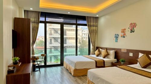 a hotel room with two beds and a large window at Xanh Tốt Hotel - FLC Sầm Sơn in Sầm Sơn
