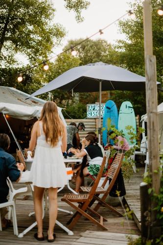a woman in a white dress is standing on a deck at Aparra Surfcamp Auberge Capbreton in Capbreton