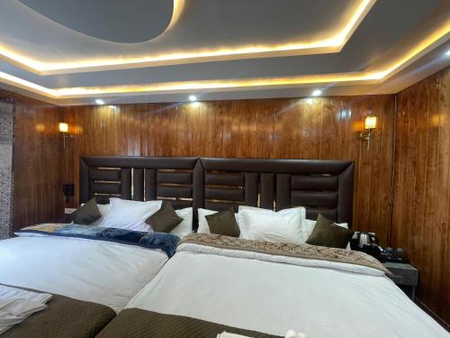 two beds in a bedroom with wooden walls at Hotel Sounsar and Restaurant in Sonāmarg