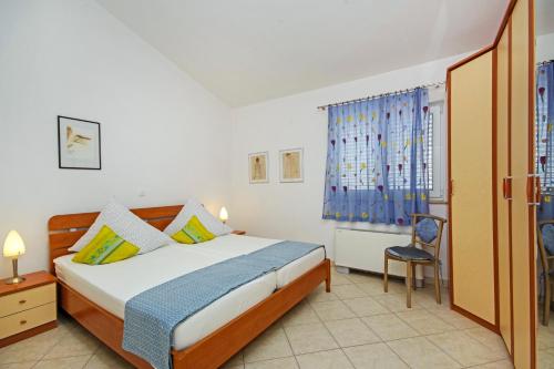 a bedroom with a bed and a chair and a window at Apartmani Villa Antonio in Makarska