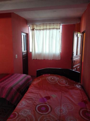 a bedroom with red walls and a bed and a window at Hostal Puerto Alegre in Copacabana
